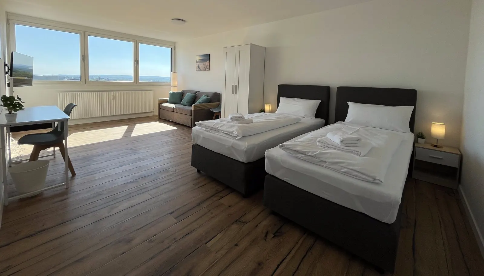 Zimmer der Beispielwohnung in Heilbronn: zwei Einzelbetten, Schreibtisch am Fenster, Sofa und Kleiderschrank